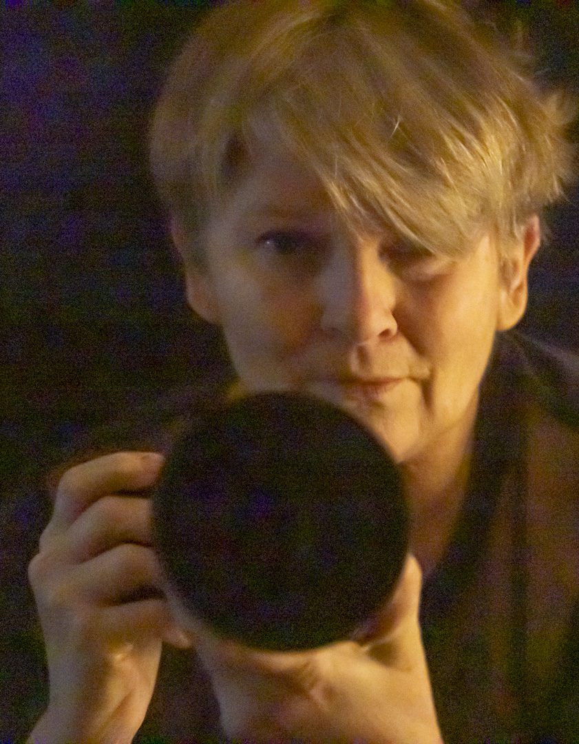 Porträtt av Kim Ritthagen med kamera, mot bakgrund av natur.